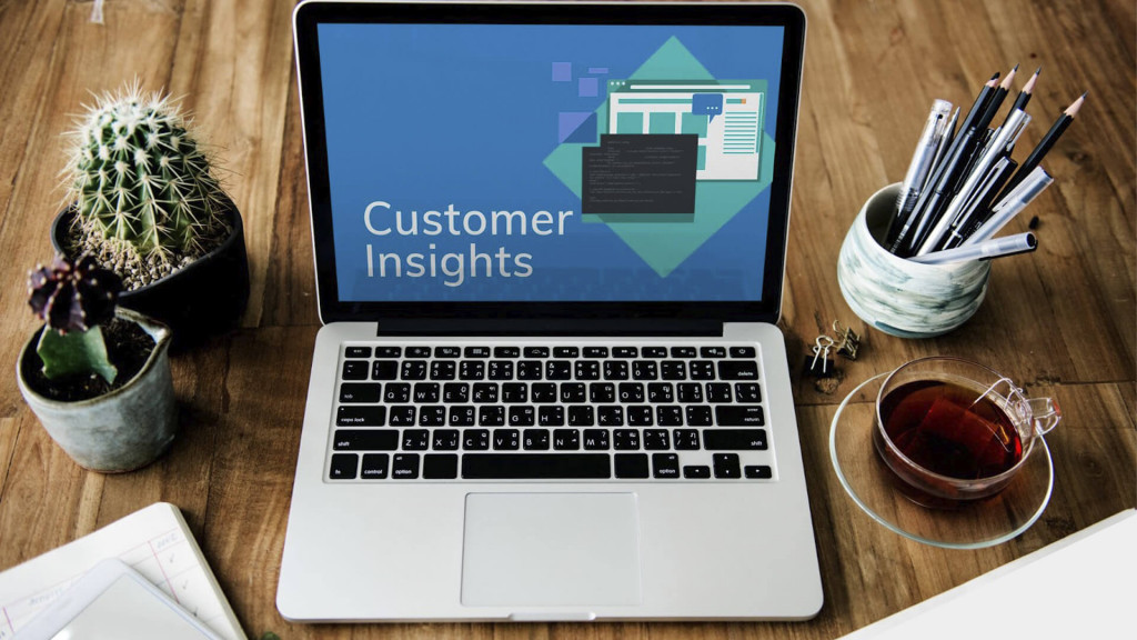 Notebook aberto em uma mesa de trabalho, com a tela exibindo a imagem "Customer Insights".